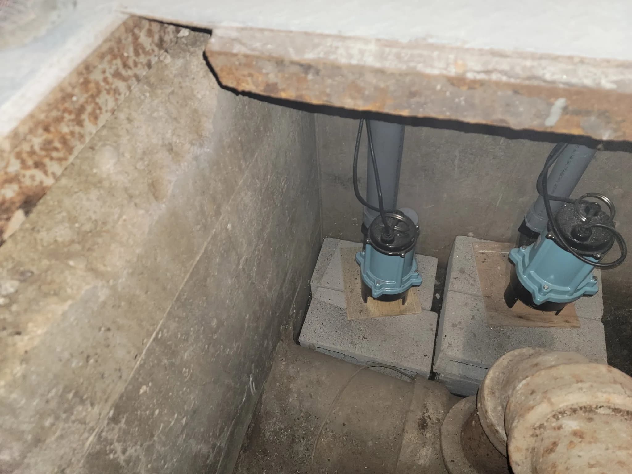 Two sewage ejector pumps installed side by side in a below-grade pit