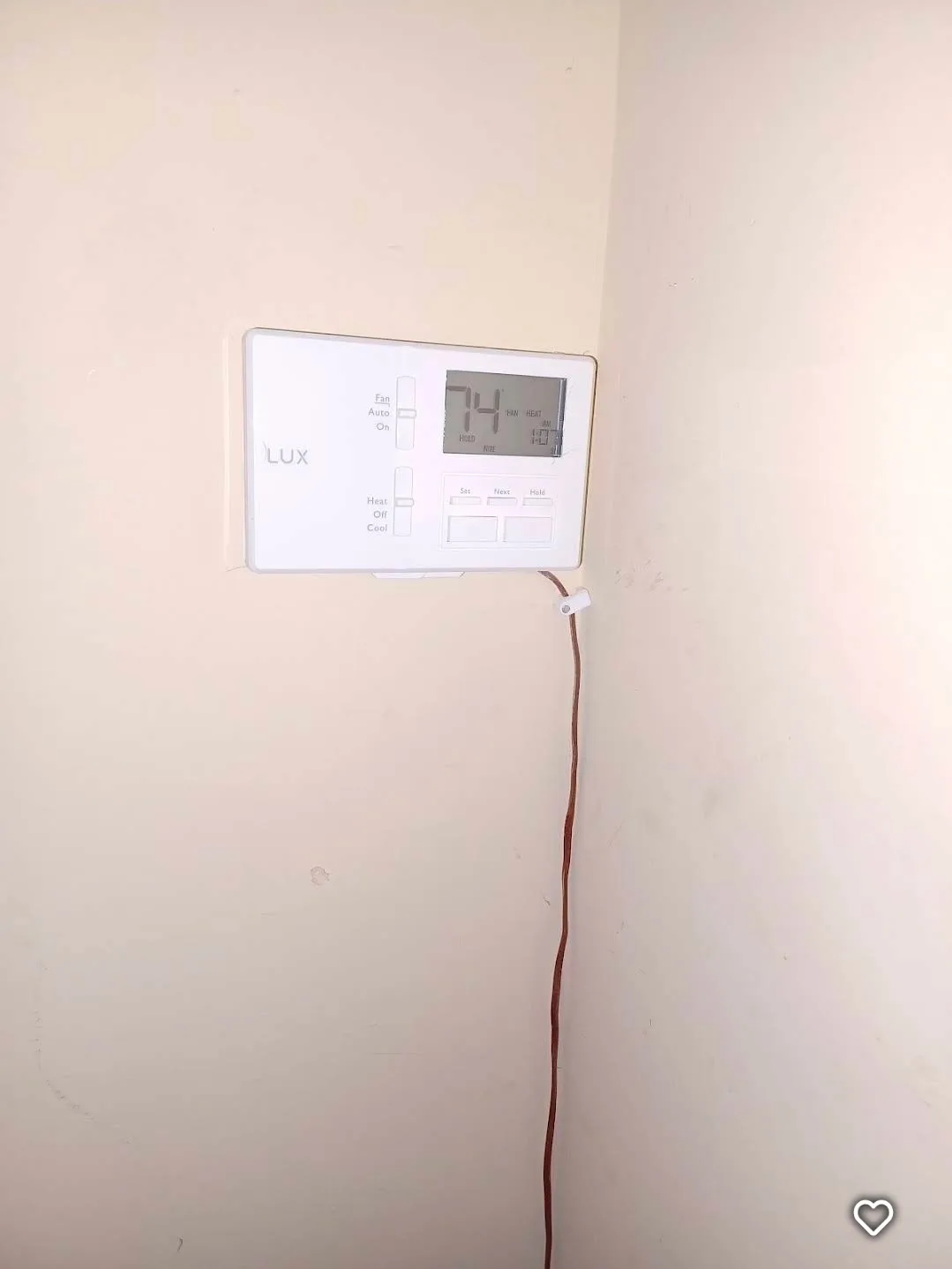 Newly installed wall-mounted thermostat, wired and displaying current temperature