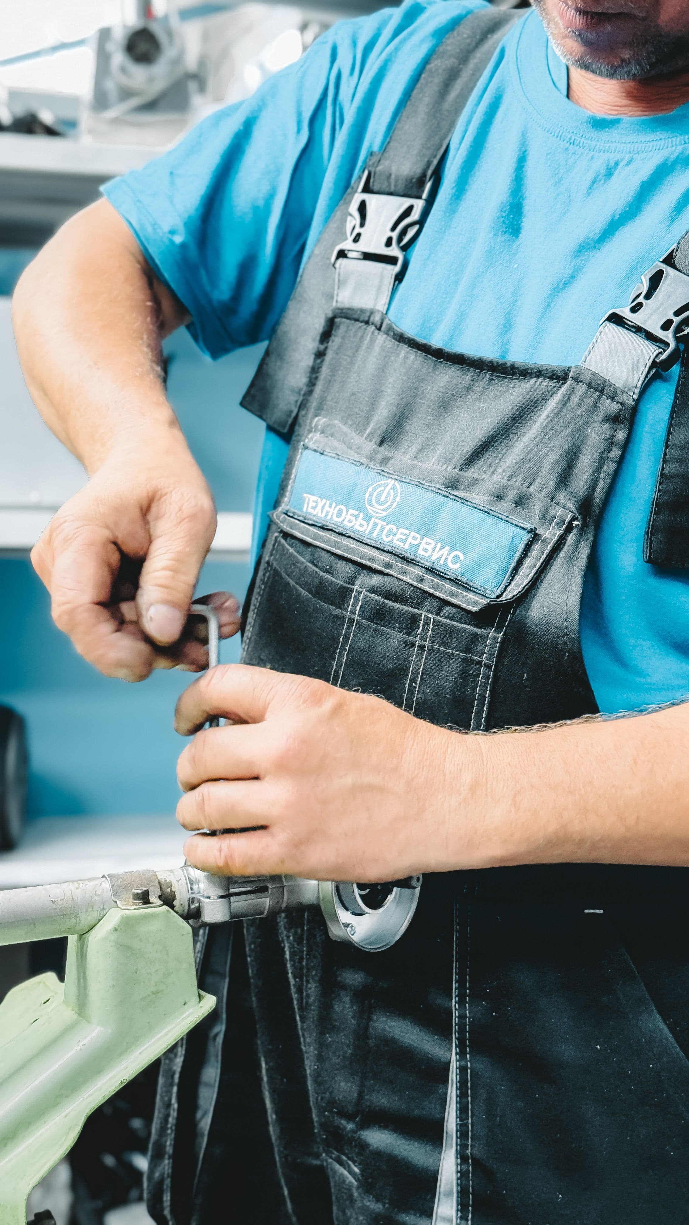 Plumber in uniform repairing a pipe with a wrench indoors