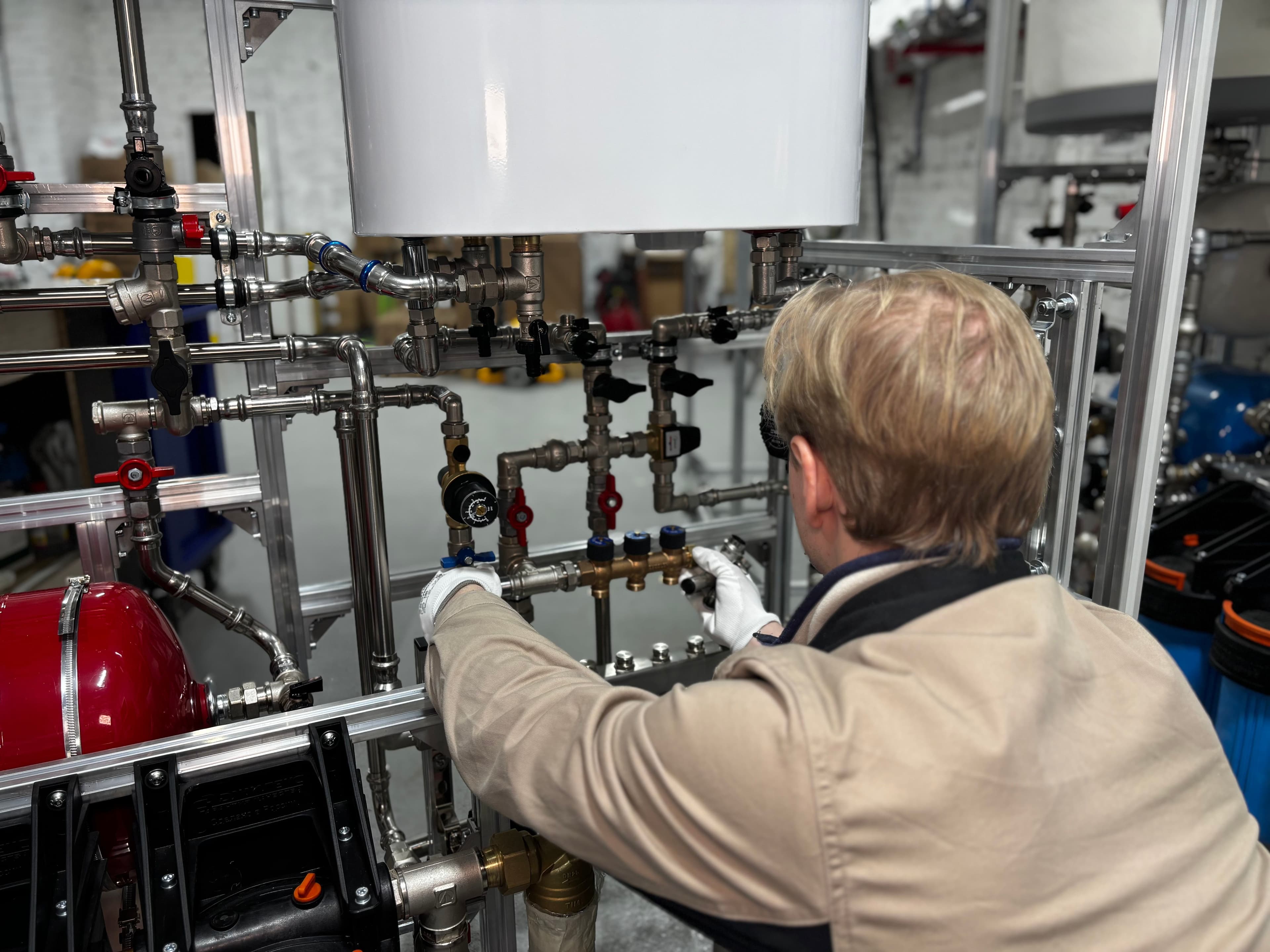 Technician working on a water heating system's valves and pressure tank
