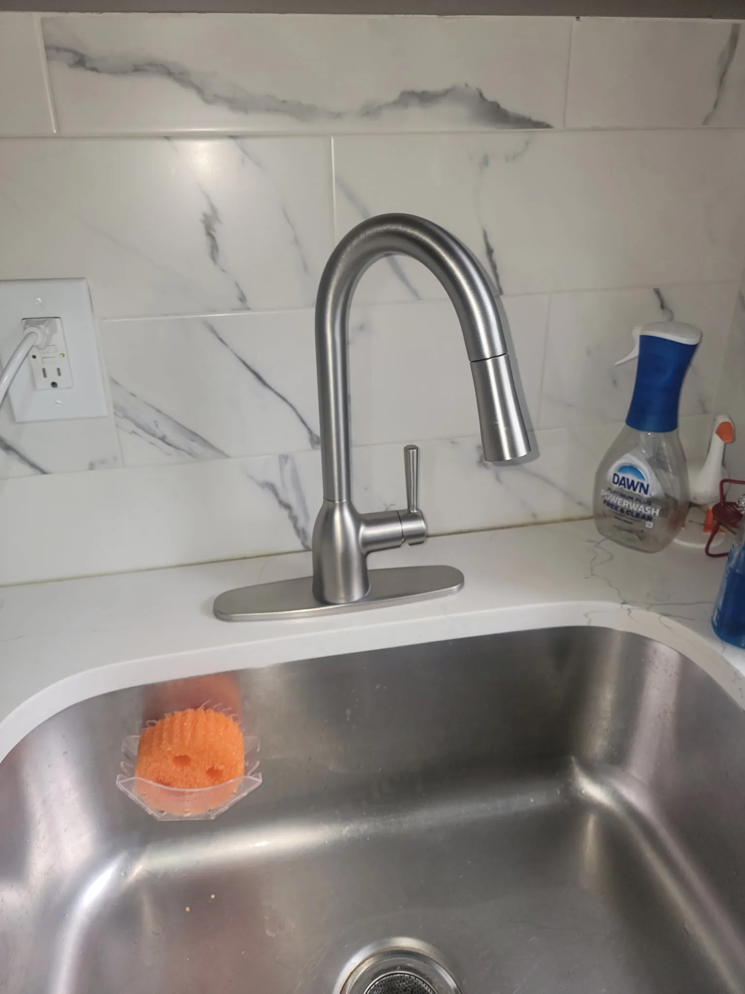 Newly installed pull-down kitchen faucet with marble backsplash