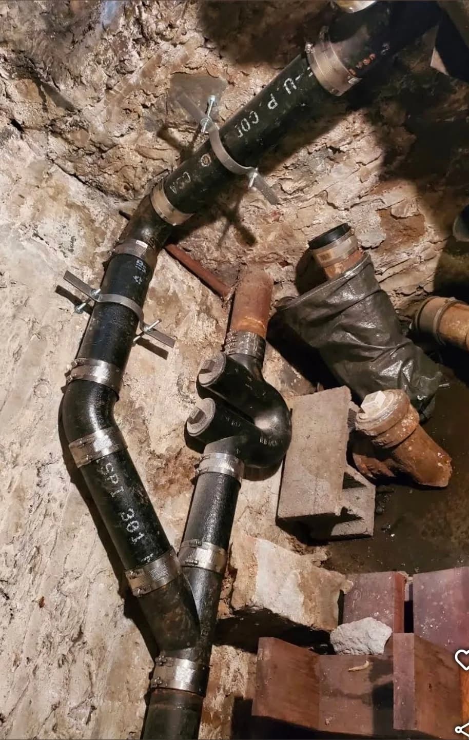 Repaired sewer line with new coupling clamps in a residential crawlspace