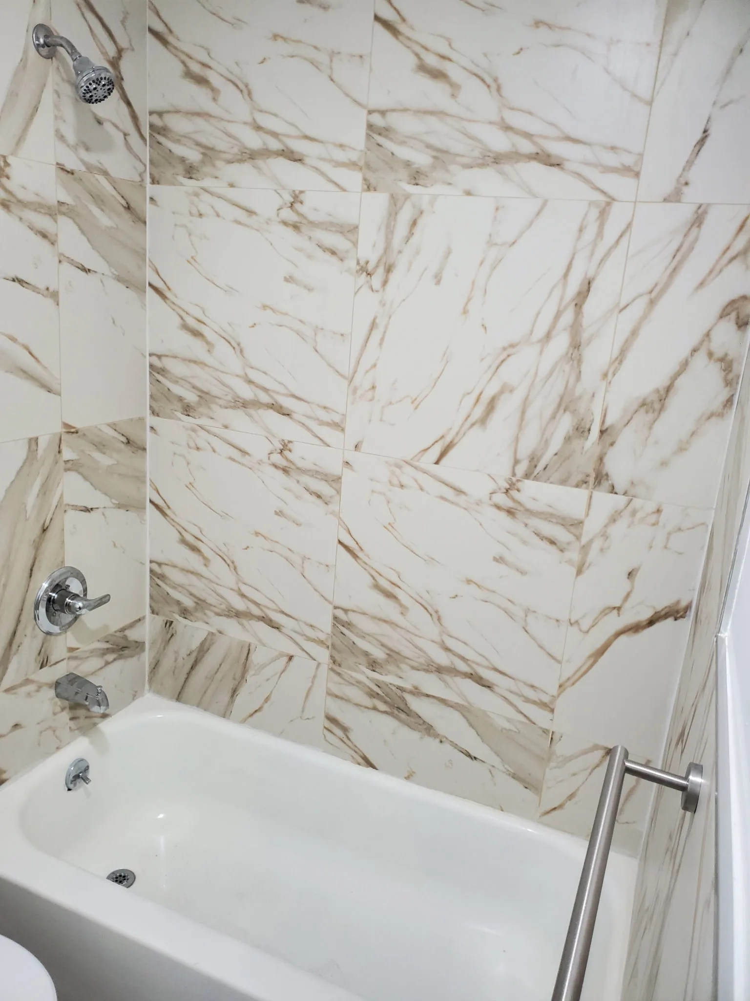Newly installed bathtub with tile surround and chrome fixtures